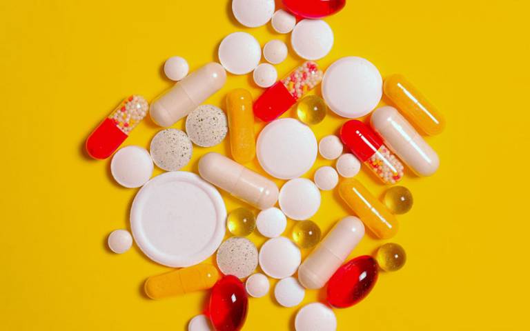 Pills of multiple colours and sizes on an orange background