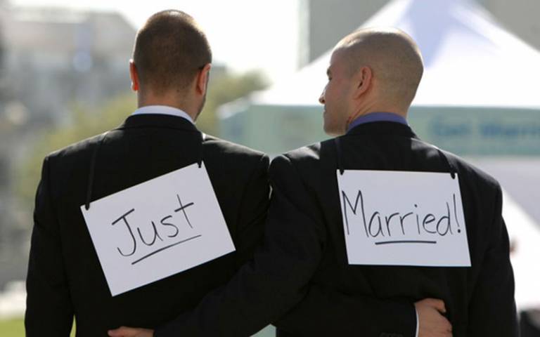 Image of two men with 'just married' signs stuck to their backs
