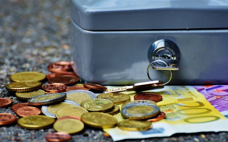 IMAGE: Money box on a pile of paper money and coins