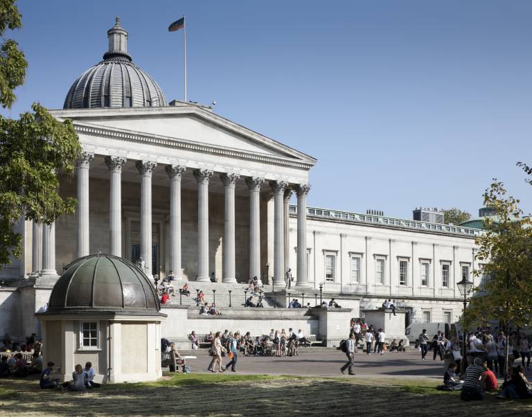 The outside of the main UCL Portico building, with people walking in front and sitting outside