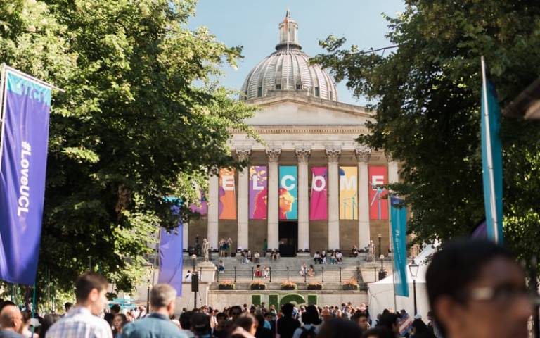 The UCL Portico building with a sign saying "WELCOME". In front of the building is a crowd of people.