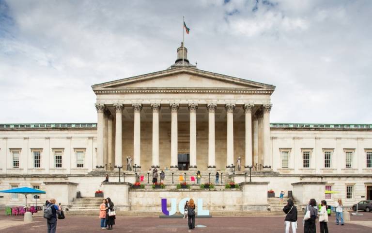 The UCL portico building and front quad. In front of the building, people are standing and walking around