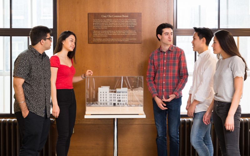 Five UCL Laws students standing around a model of Bentham House and talking