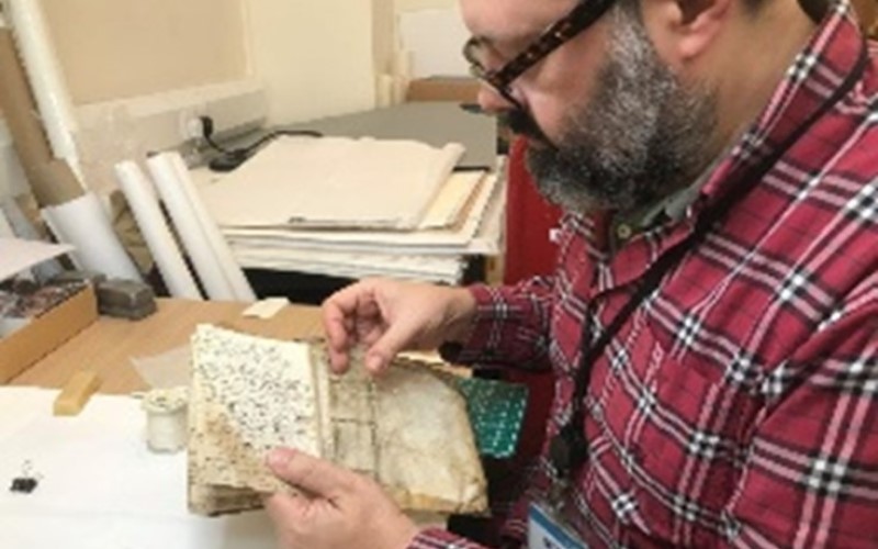 Member of staff handling a small rare book