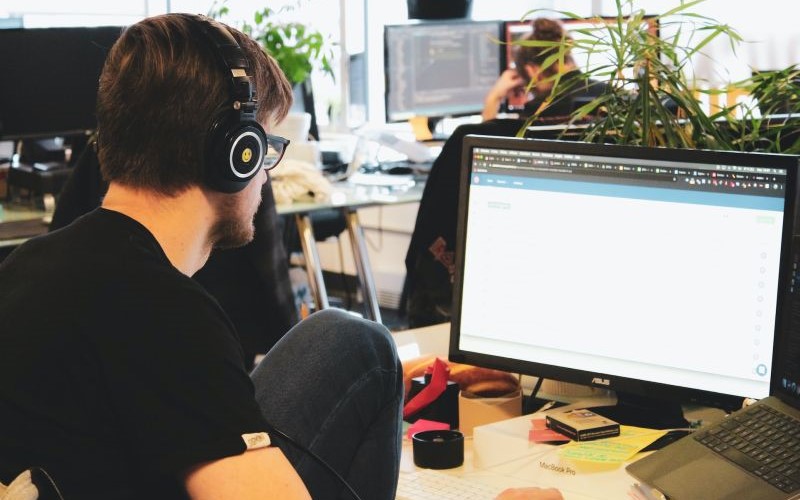 Man using a desktop computer whilst wearing headphones