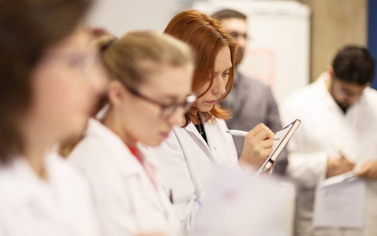 A group of medics in white lab coats participate in knowledge exchange.