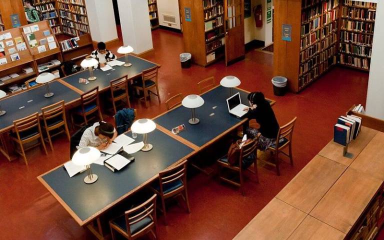 Students studying in the UCL Main Library in the Wilkins building, viewed from above.