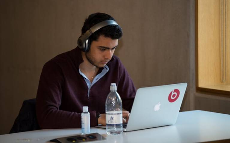 Student working on laptop, wearing headphones