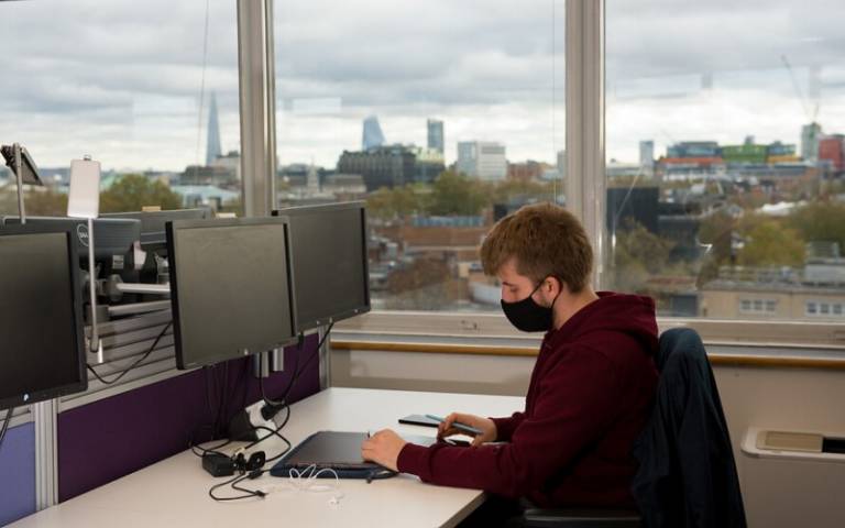 Student studying, wearing a face mask with London in window view