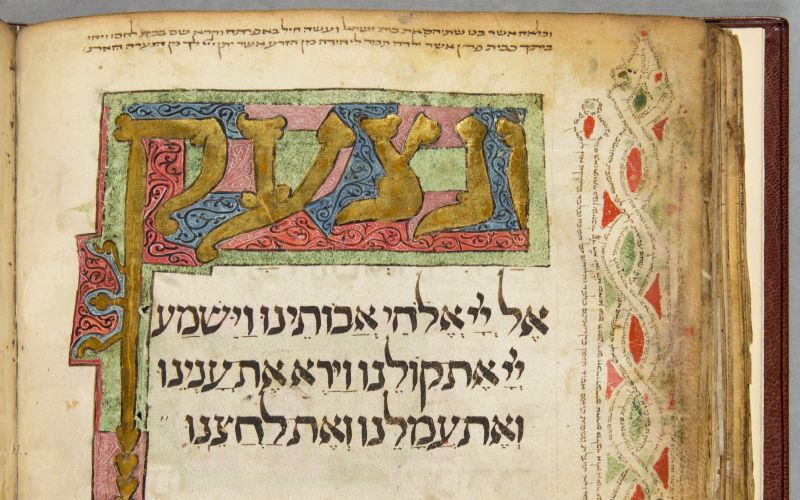 A page of a book with gold leaf Hebrew script at the top and bottom of the page surrounded by green, blue and pink or red patterns.  In the centre is black Hebrew script and sitting vertically on the right side is a red, black and green wavy design.
