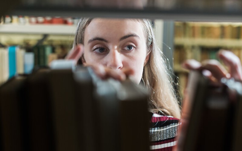 Library user looking at items on book shelf, close up