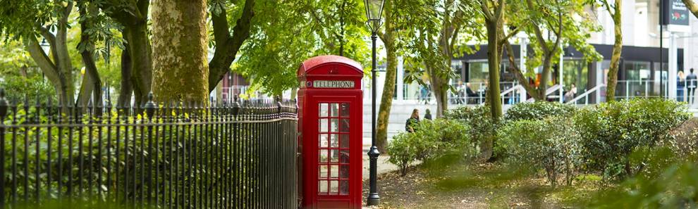 A park with a telephone box in front of the UCL School of Pharmacy