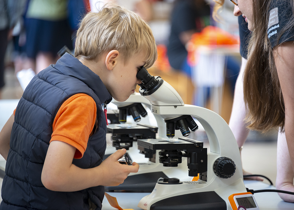 Boy looking down microscope at science fair
