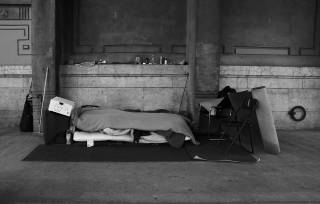 black and white photo of a homeless person sleeping on street