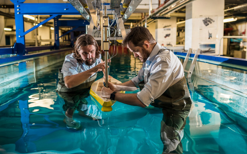 Two engineers conducting a naval architecture experiment in a water tank