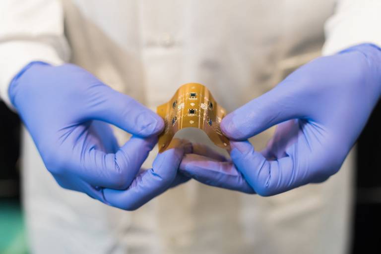 a photo of a researcher in gloves holding nanoscale printed circuitboard