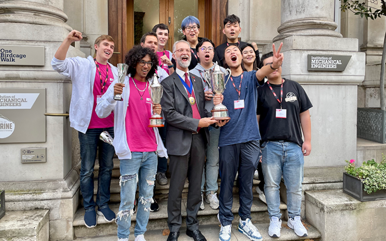 UCL students holding trophies outside a doorway