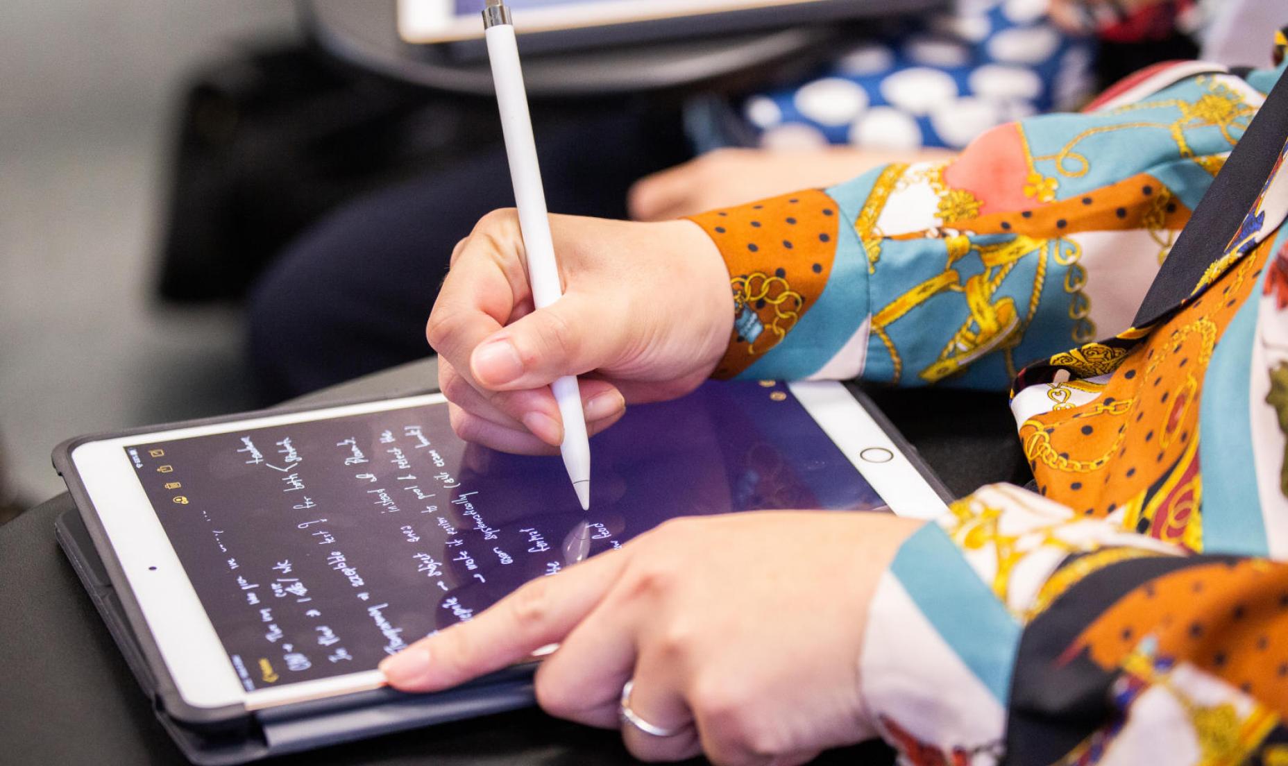 A person writes on an electric tablet with a stylus pen