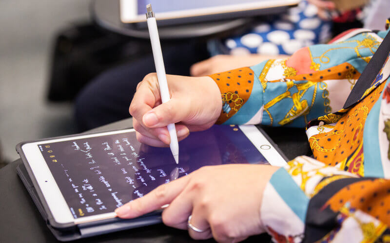 A conference attendee makes notes with a stylus pen on an iPad