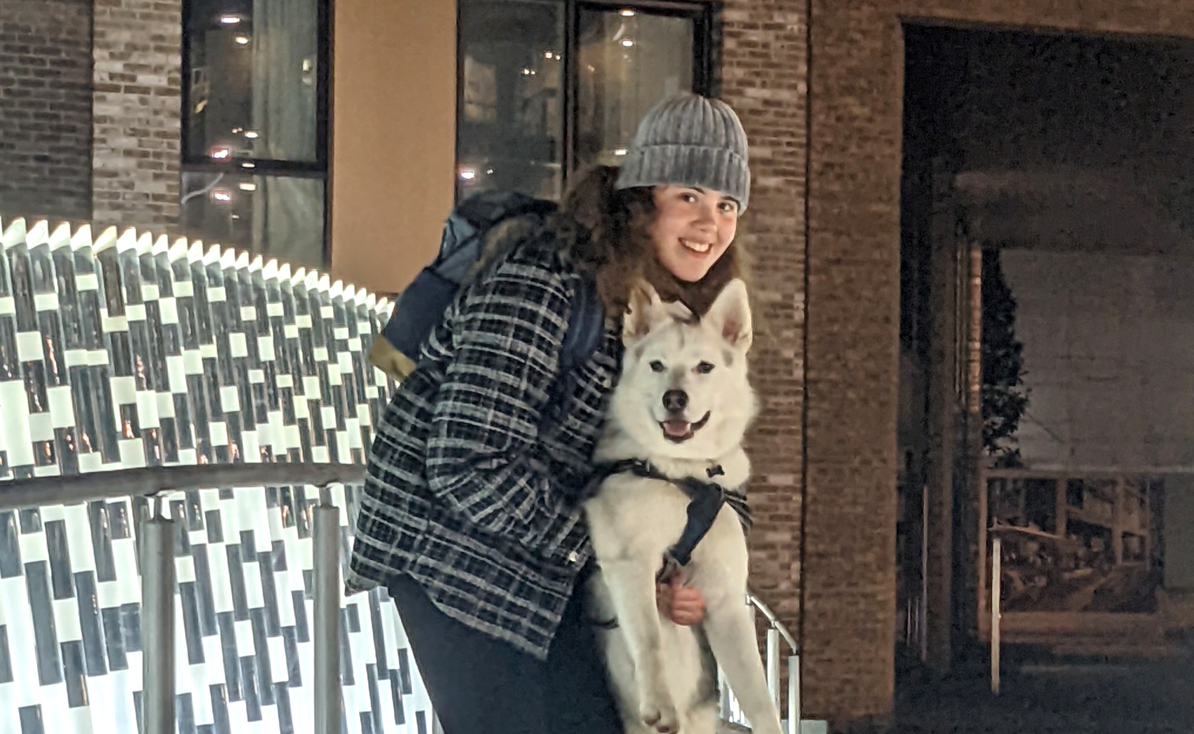 student hugging a husky dog in the snow