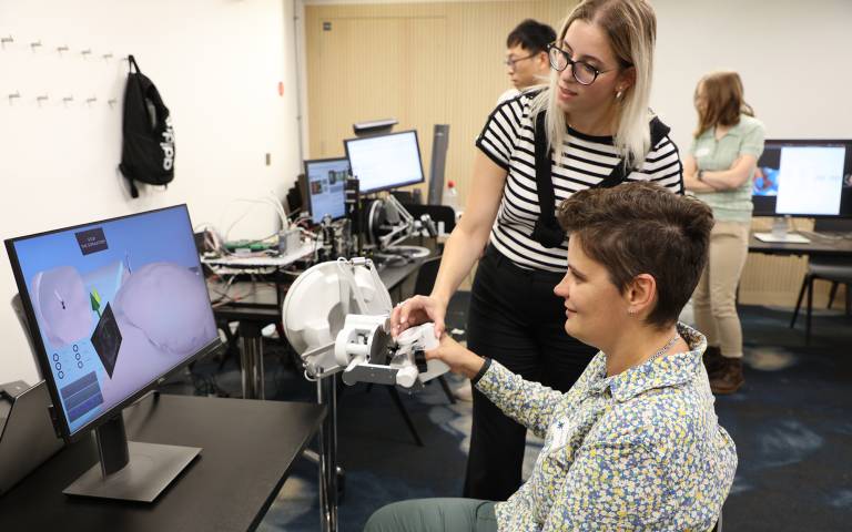 Woman and researcher operating a robotic arm