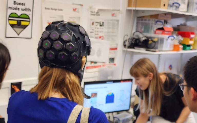 students in the lab, one girl wearing a headset, in the background you can see a computer screen