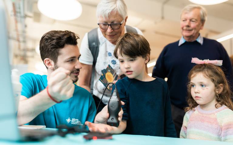 a boy with his little sister and grandparents being shown an ultrasound machine by a male researcher