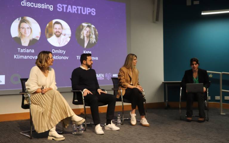four people, three women and one man, sitting on a stage as part of a panel discussion on tech start-ups