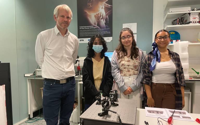 A photograph of Prof Peter Munro in the lab with three placement students