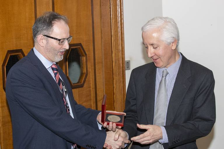 Jem Hebden shakes hands with Andy Hebden and receives an award for his Joel Lecture
