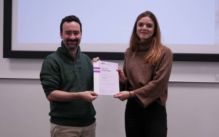 Female student holding a certificate with a male academic