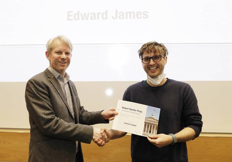 Student shaking the hand of an academic holding a certificate