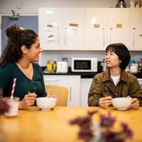 Two female students sitting together with a cup of tea in their kitchen