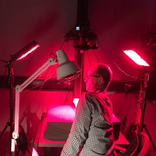 Prof Adam Gibson sitting in red light infront of a multispectral imaging device