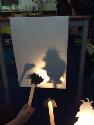 Children holding cut out pictures of the Gruffalo creating shadow puppets