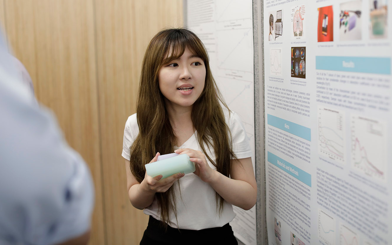 Female student presenting her research on a poster