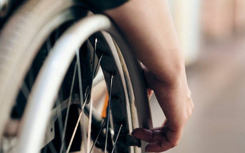 Close-up shot of a wheelchair wheel, with hands operating movement