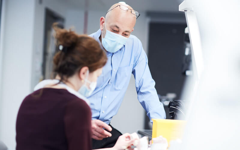 Two people in surgical mask in a lab at the Eastman Dental Institute