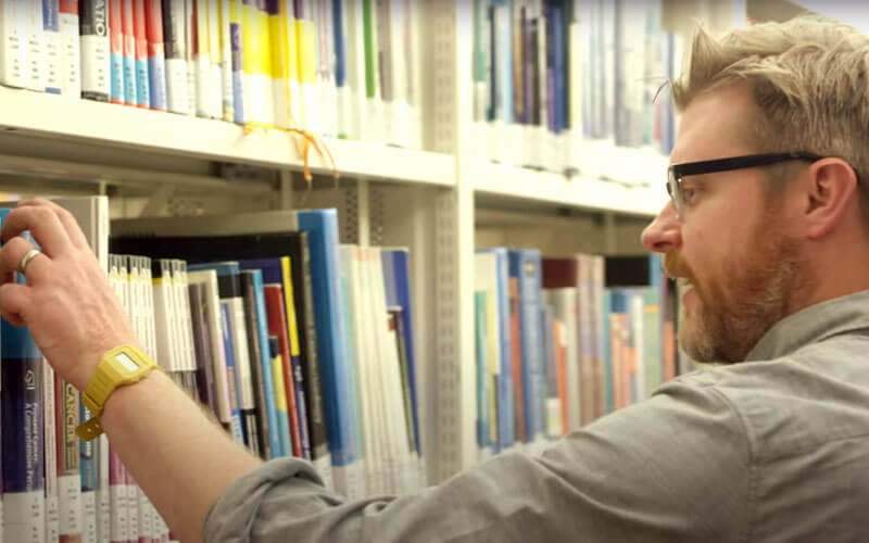 Professor Gavin Jell takes a book from library shelves