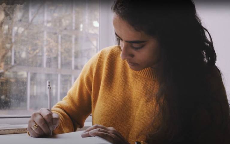 UCL student Shreya sat at a window writing