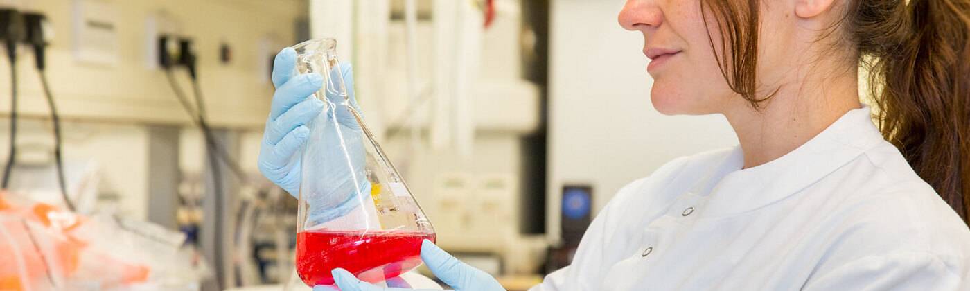 A member of staff examines a formula in a glass jar in the Cancer Institute