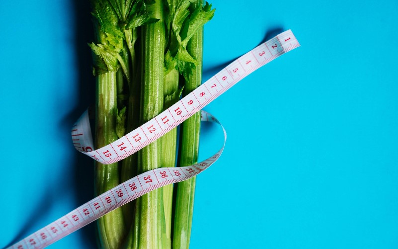 A celery bunch surrounded by a measuring tape 