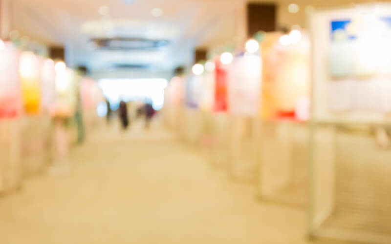 Blurred image of a poster display on stands in a bright room