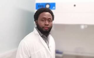 Tope Oyelade wearing a lab coat whilst working in the lab. Portrait image