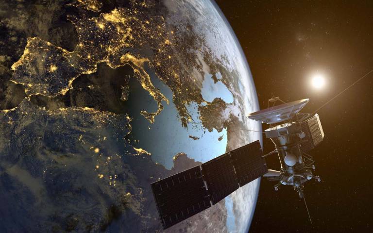 satellite orbiting Earth with cities illuminated at night