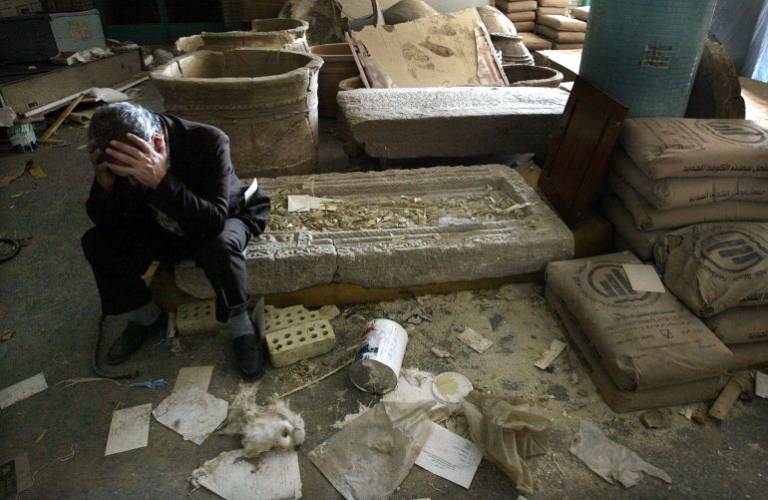 Iraqi National Museum Deputy Director Mushin Hasan holds his head in his hands as he sits on destroyed artefacts in Baghdad in April 2003