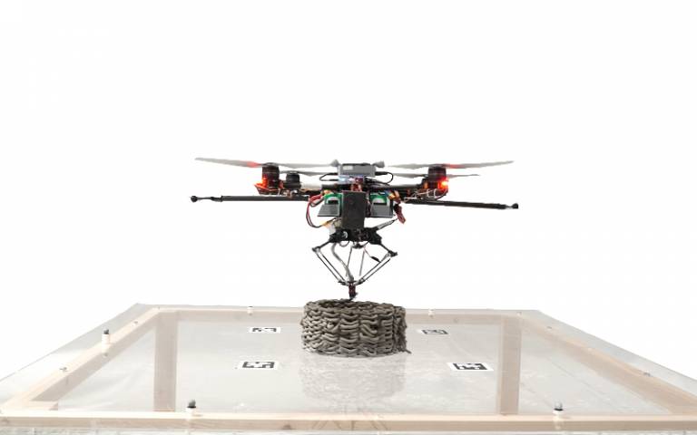 A flying drone deposits a layer of concrete on top of a cylinder of concrete