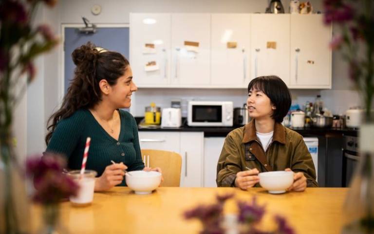 two students talking in a kitchen