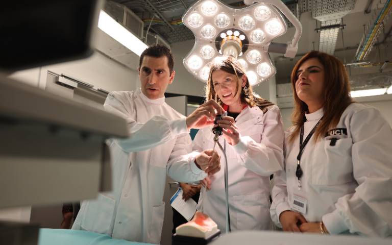 Three people in lab coats operate an endoscope.