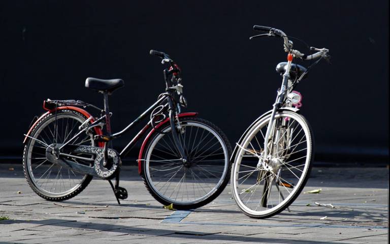 Two bicycles standing on a pavement